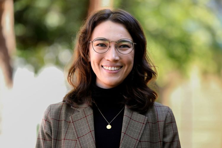 Person in business attire smiling in an outdoor setting